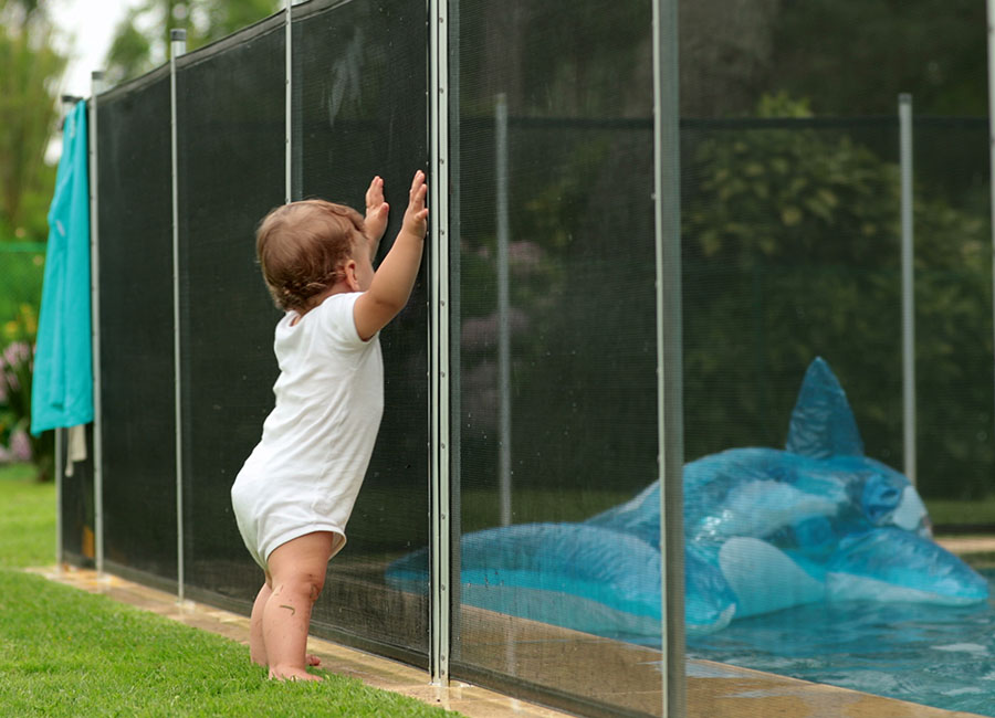 Un bébé s'appuyant sur la clôture d'une piscine