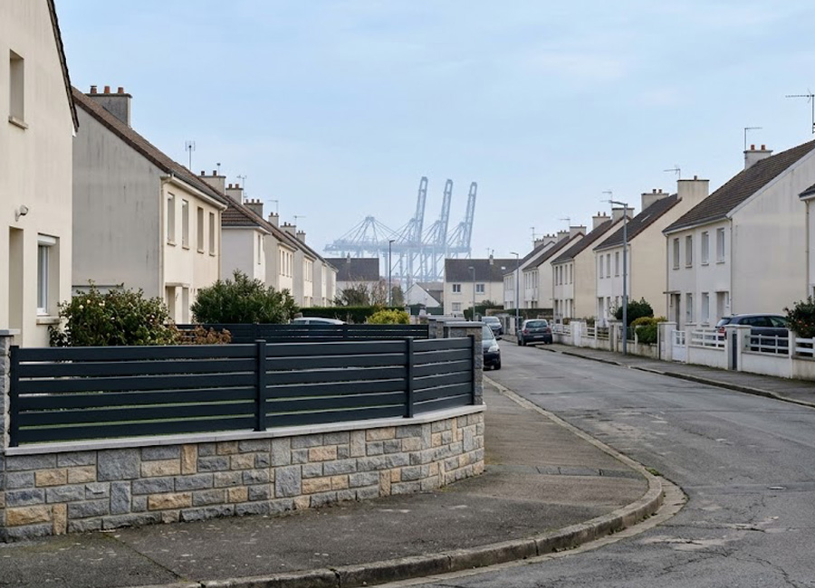 Clôture aluminium sombre posée sur un muret bas dans une rue résidentielle de Saint-Nazaire